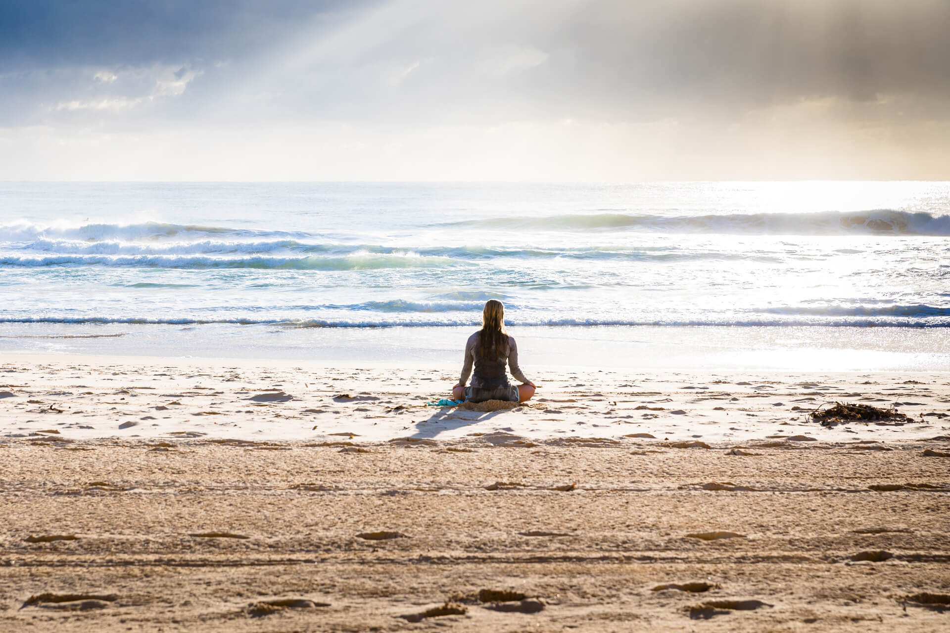 A person standing on top of a sandy beach next to the ocean

            Description automatically generated